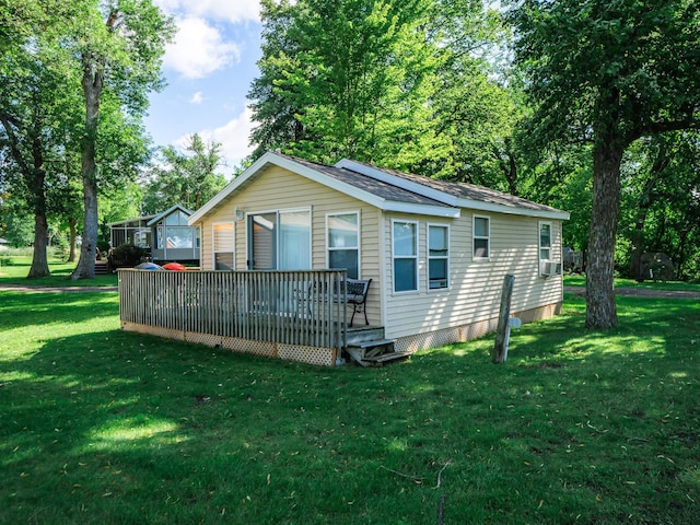 view of property exterior with a garage, a deck, an outbuilding, cooling unit, and a yard