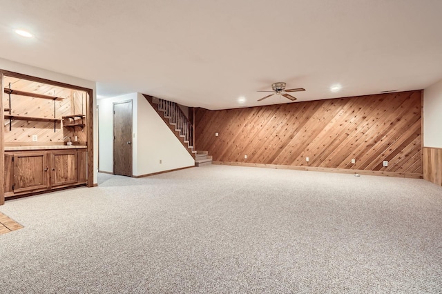 finished below grade area featuring carpet flooring, recessed lighting, wood walls, and stairway