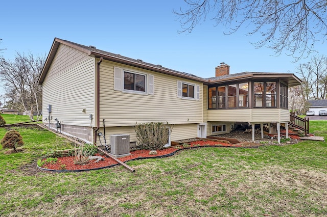 back of property featuring a sunroom, a yard, a chimney, and cooling unit