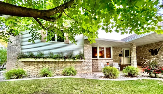 exterior space with brick siding and a yard