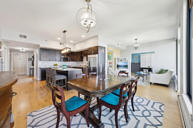 dining area with recessed lighting, visible vents, a baseboard heating unit, light wood-style floors, and a chandelier