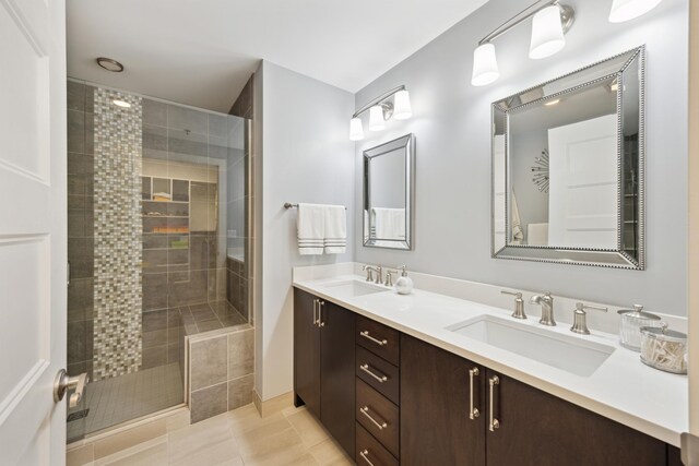 bathroom featuring tile patterned flooring, an enclosed shower, and dual bowl vanity