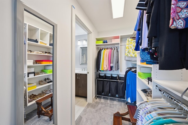 walk in closet with a skylight, light carpet, and a sink