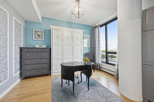 home office with baseboards, light wood finished floors, a baseboard radiator, and a notable chandelier