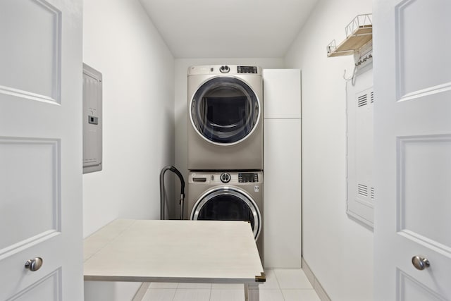 clothes washing area featuring stacked washer / dryer, laundry area, electric panel, and light tile patterned floors