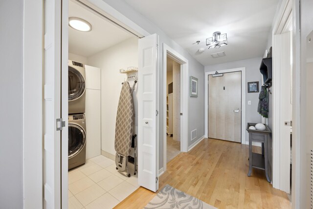 laundry room with light hardwood / wood-style flooring and stacked washing maching and dryer