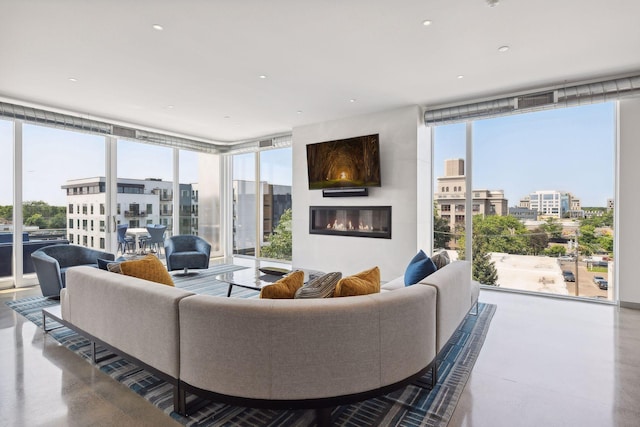 living room with concrete flooring, a large fireplace, and floor to ceiling windows