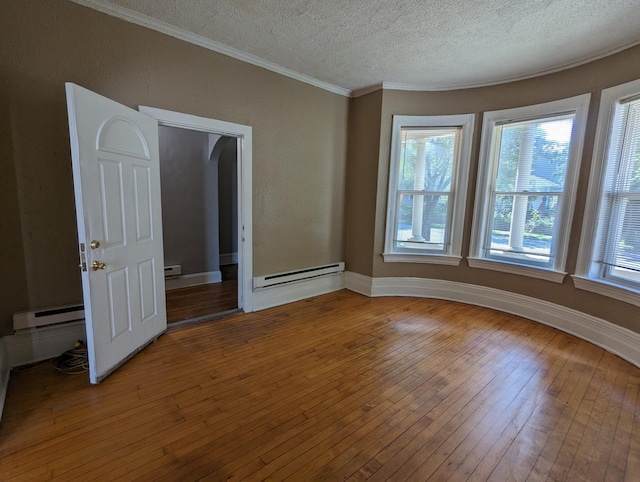 empty room featuring a baseboard radiator, hardwood / wood-style flooring, a textured ceiling, crown molding, and baseboard heating