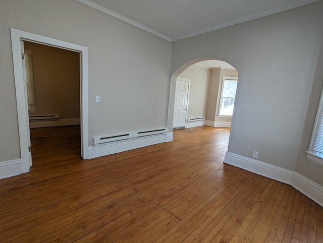 empty room featuring ornamental molding, hardwood / wood-style flooring, arched walkways, a baseboard radiator, and baseboards