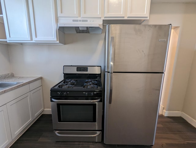 kitchen featuring dark wood-type flooring, light countertops, appliances with stainless steel finishes, under cabinet range hood, and white cabinetry