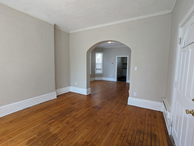 unfurnished room featuring ornamental molding, a textured ceiling, hardwood / wood-style floors, arched walkways, and baseboards