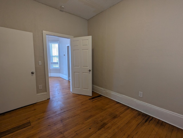 spare room with baseboards and hardwood / wood-style floors