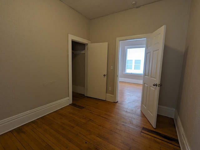 unfurnished bedroom featuring baseboards and hardwood / wood-style flooring