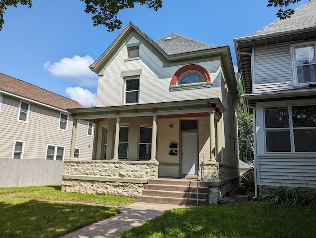 view of front facade featuring brick siding, a porch, and fence