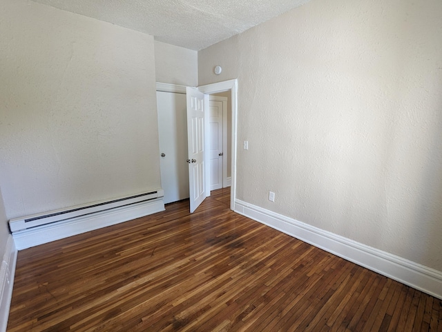 empty room featuring a textured wall, a baseboard heating unit, a textured ceiling, and hardwood / wood-style flooring