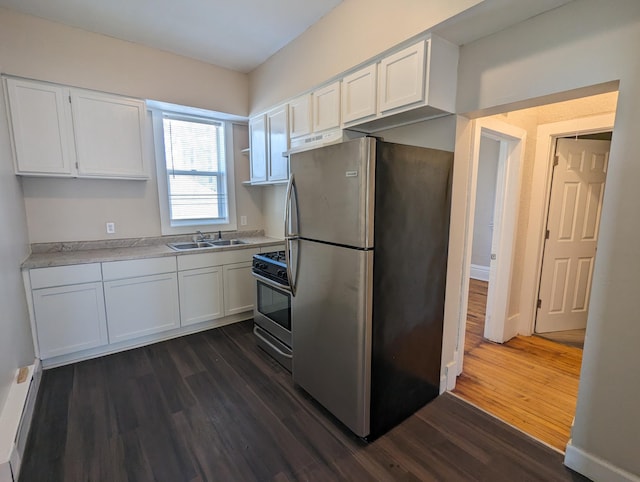 kitchen featuring dark wood finished floors, white cabinetry, stainless steel appliances, and a sink