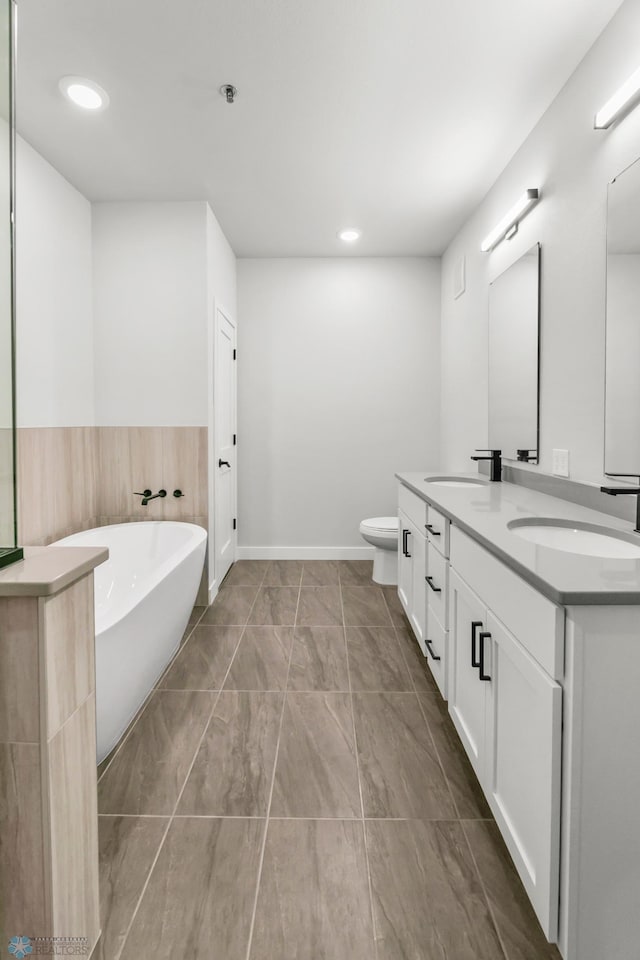 bathroom with vanity, a bathing tub, and toilet