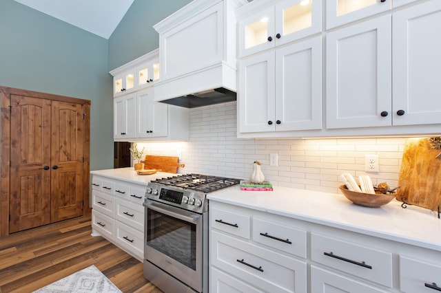 kitchen with dark wood-type flooring, custom range hood, gas stove, white cabinets, and decorative backsplash