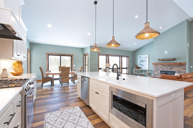 kitchen featuring an island with sink, white cabinets, hanging light fixtures, custom exhaust hood, and stainless steel appliances