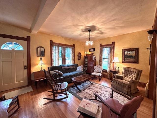 living room with beamed ceiling, a chandelier, and hardwood / wood-style flooring