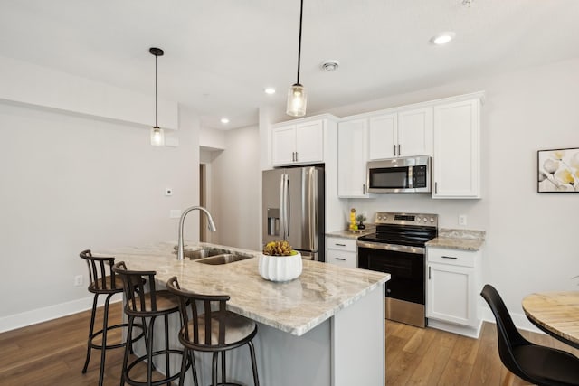 kitchen with white cabinetry, pendant lighting, appliances with stainless steel finishes, and a kitchen island with sink