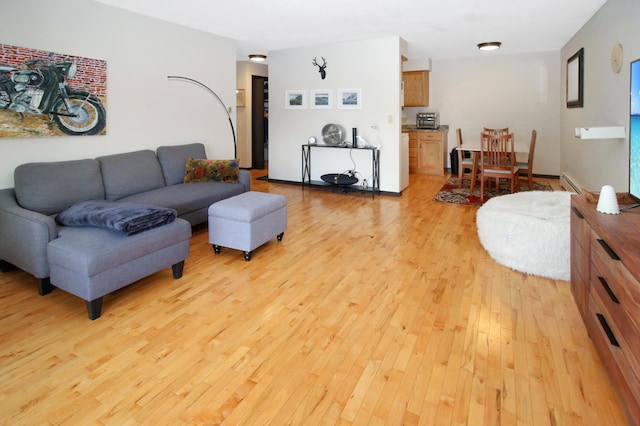 living room with a baseboard heating unit and light wood-style floors