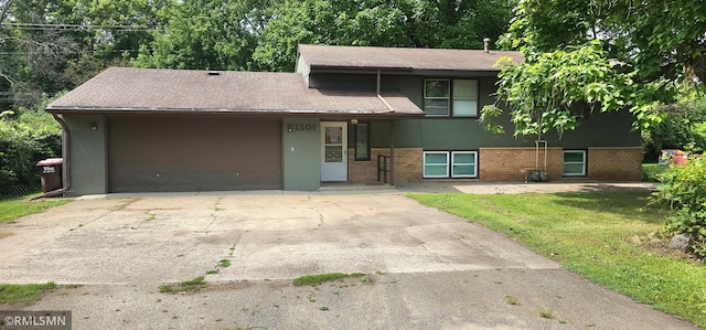 split level home featuring an attached garage, stucco siding, concrete driveway, and brick siding