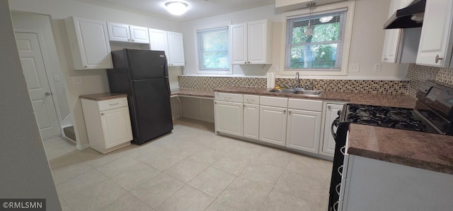 kitchen featuring sink, backsplash, white cabinetry, black refrigerator, and wall chimney exhaust hood