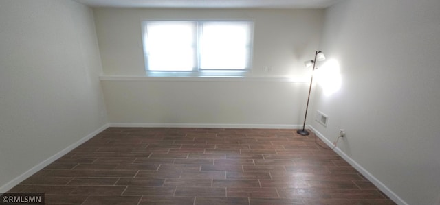 unfurnished room featuring dark wood-style flooring, visible vents, and baseboards