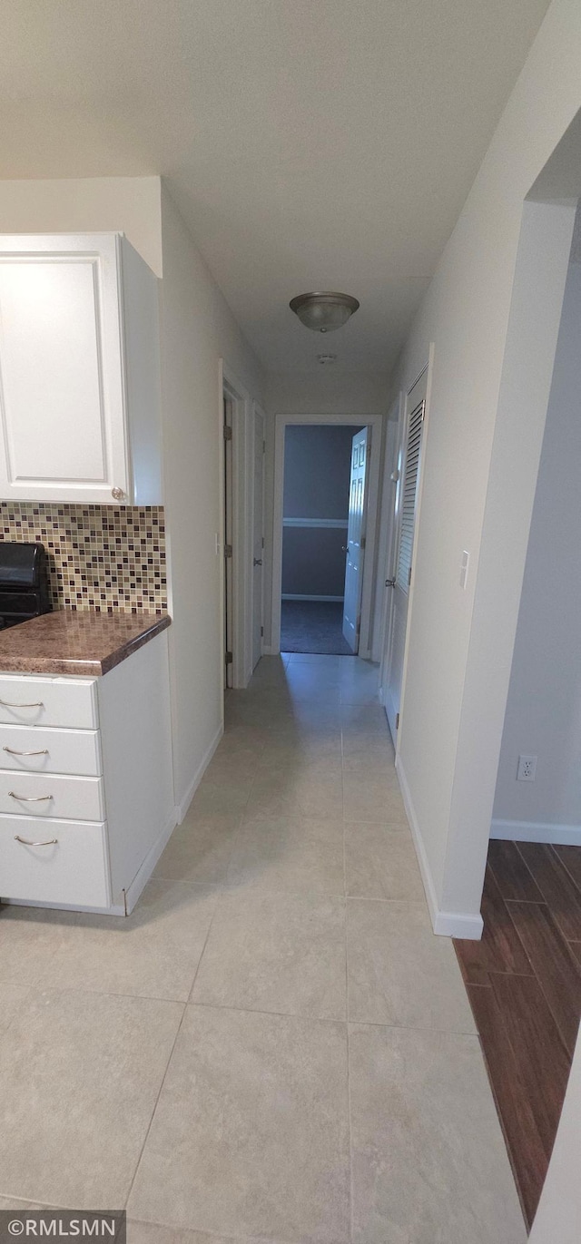 hall featuring light tile patterned flooring and baseboards