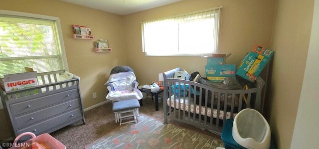 carpeted bedroom featuring multiple windows and a nursery area