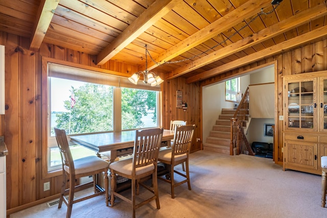 dining area with wooden ceiling, wooden walls, a chandelier, and light carpet