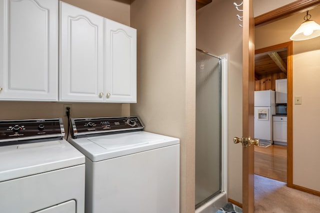 washroom featuring cabinets, light colored carpet, and washer and clothes dryer