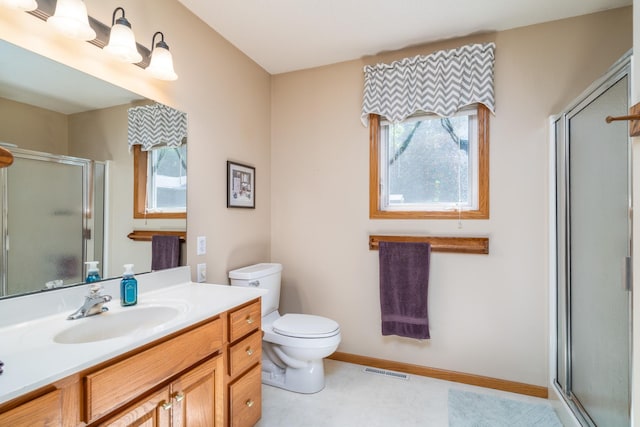 bathroom with tile patterned floors, vanity, a shower with door, and toilet