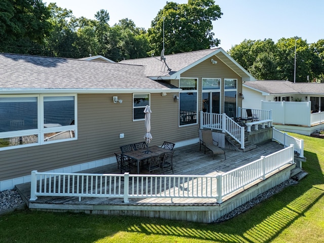 rear view of house featuring a wooden deck and a yard