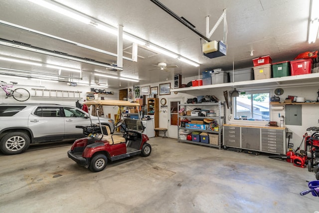 garage featuring electric panel, a garage door opener, and a workshop area