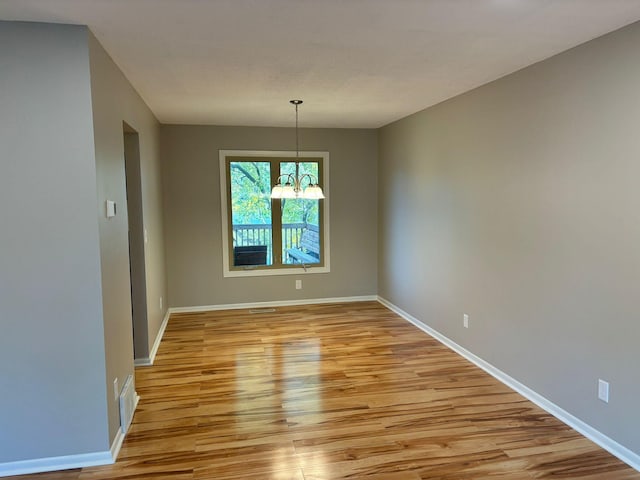 unfurnished dining area featuring a notable chandelier and light wood-type flooring