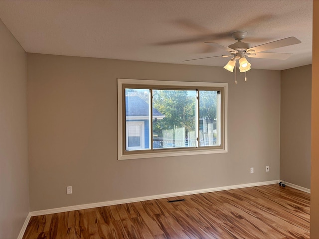 spare room with ceiling fan, a textured ceiling, and light wood-type flooring