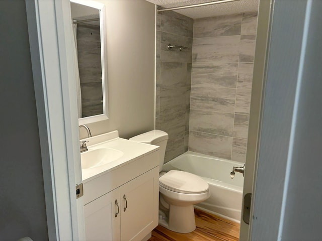 full bathroom featuring toilet, hardwood / wood-style floors, tiled shower / bath combo, vanity, and a textured ceiling