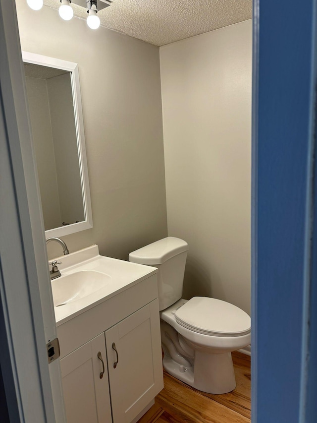 bathroom with vanity, hardwood / wood-style floors, a textured ceiling, and toilet