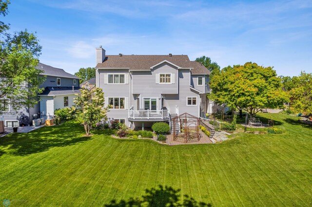 rear view of house featuring a lawn and a deck