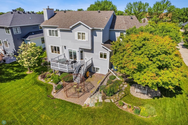 rear view of house featuring a wooden deck and a lawn