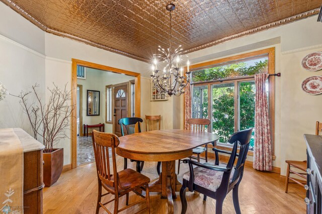 dining area featuring light wood-type flooring, crown molding, and a chandelier