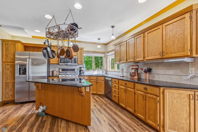 kitchen featuring appliances with stainless steel finishes, light hardwood / wood-style flooring, ornamental molding, and decorative backsplash