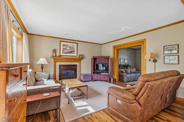 living room featuring wood-type flooring, crown molding, and a tiled fireplace