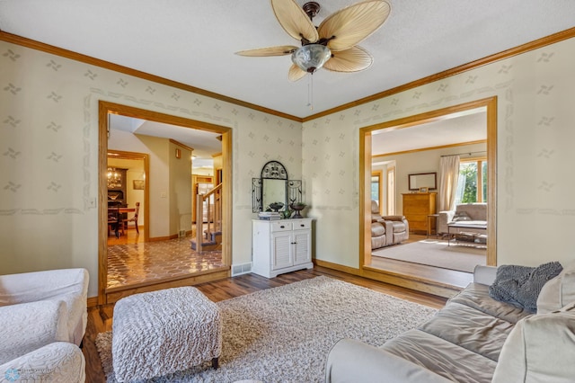 living room with ceiling fan, wood-type flooring, and crown molding