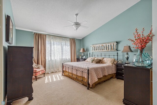 carpeted bedroom featuring ceiling fan, a textured ceiling, and vaulted ceiling