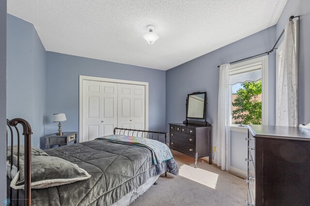 bedroom featuring a textured ceiling, carpet floors, and a closet