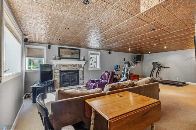 carpeted living room with a stone fireplace