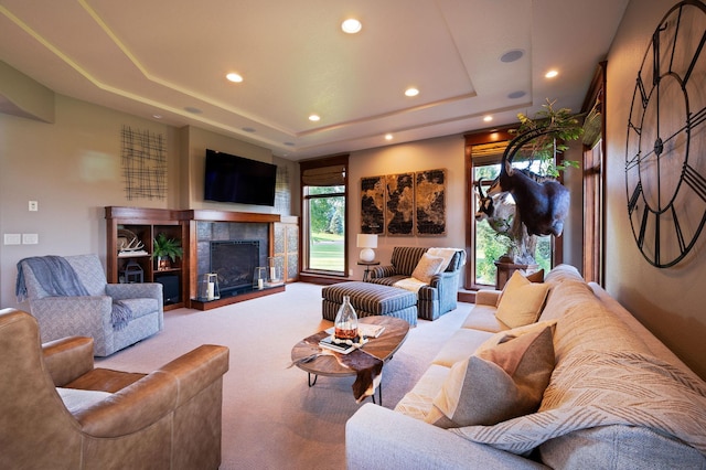 carpeted living room featuring a raised ceiling and a tile fireplace